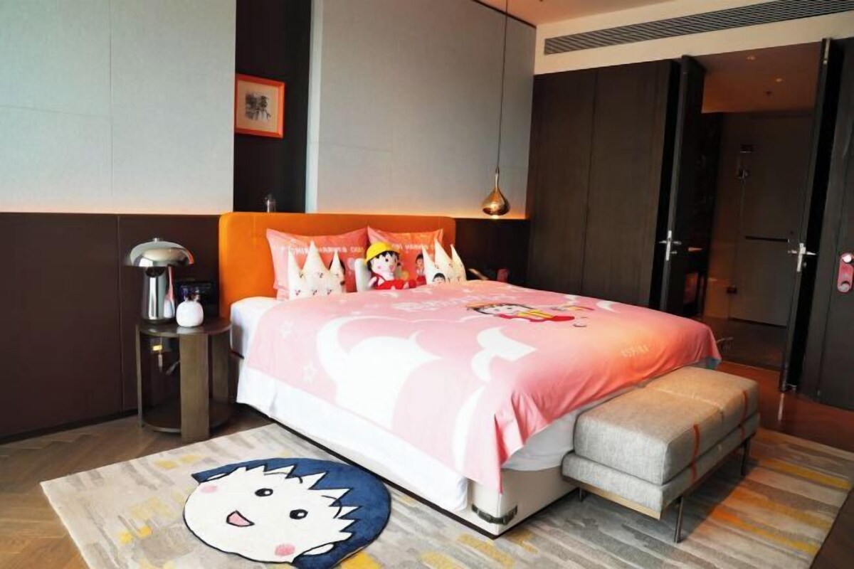 Un dormitorio con cama, mesita de noche y una alfombra decorativa.