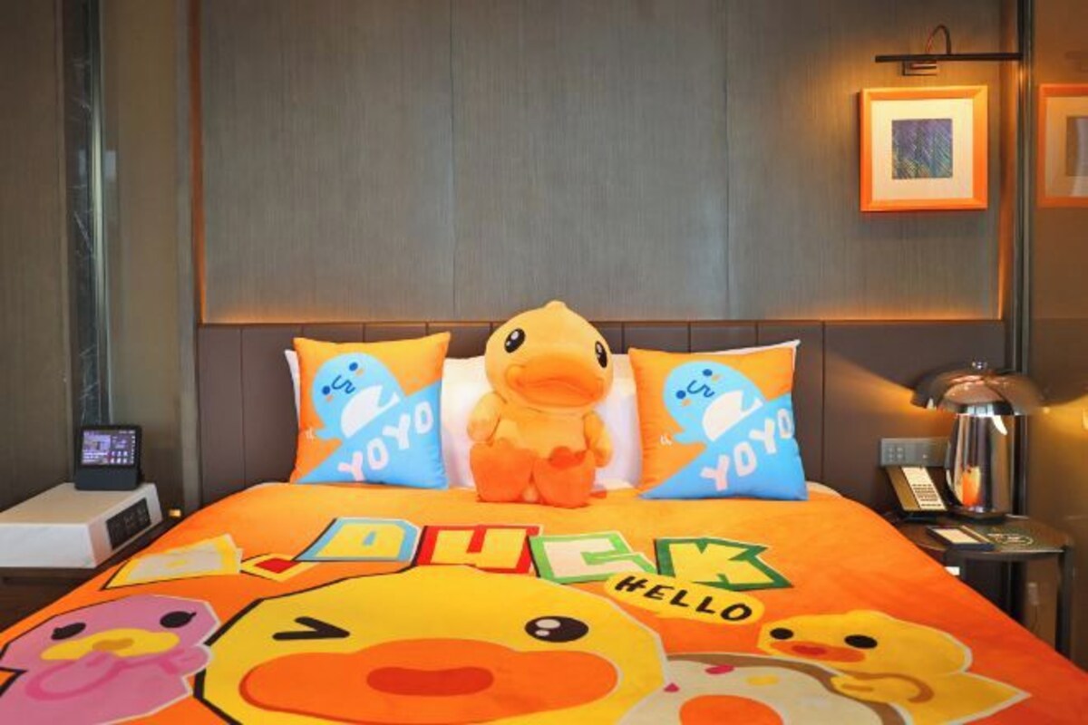 Una cama con almohadas con motivos de patos y una colcha ilustrada con patos.