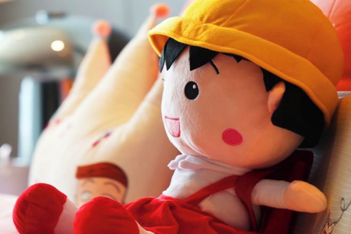 Un peluche con sombrero amarillo y vestimenta roja.