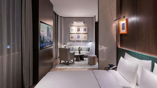 Une chambre d’hôtel moderne avec un grand lit, un canapé, une table basse et un téléviseur.