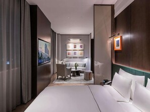 Una camera d'hotel moderna con un letto grande, un divano, un tavolino e una TV.