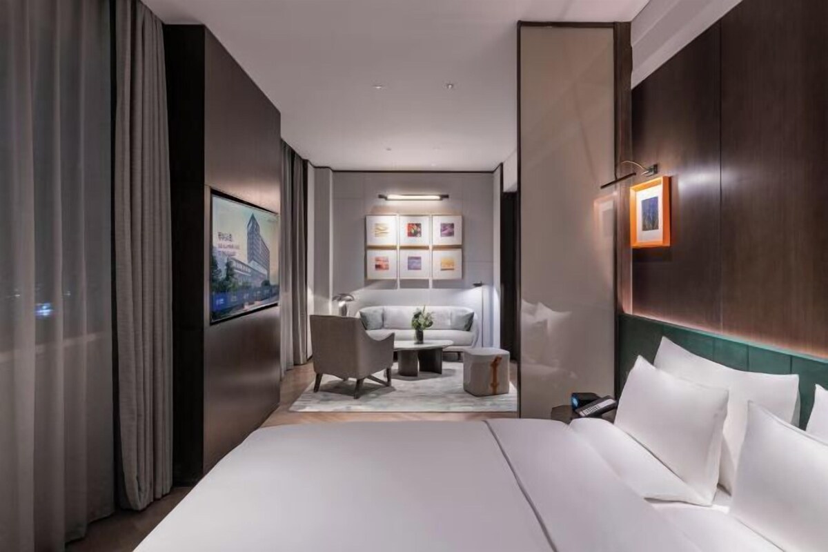 Una habitación de hotel moderna con una cama grande, un escritorio, una silla y un sofá.