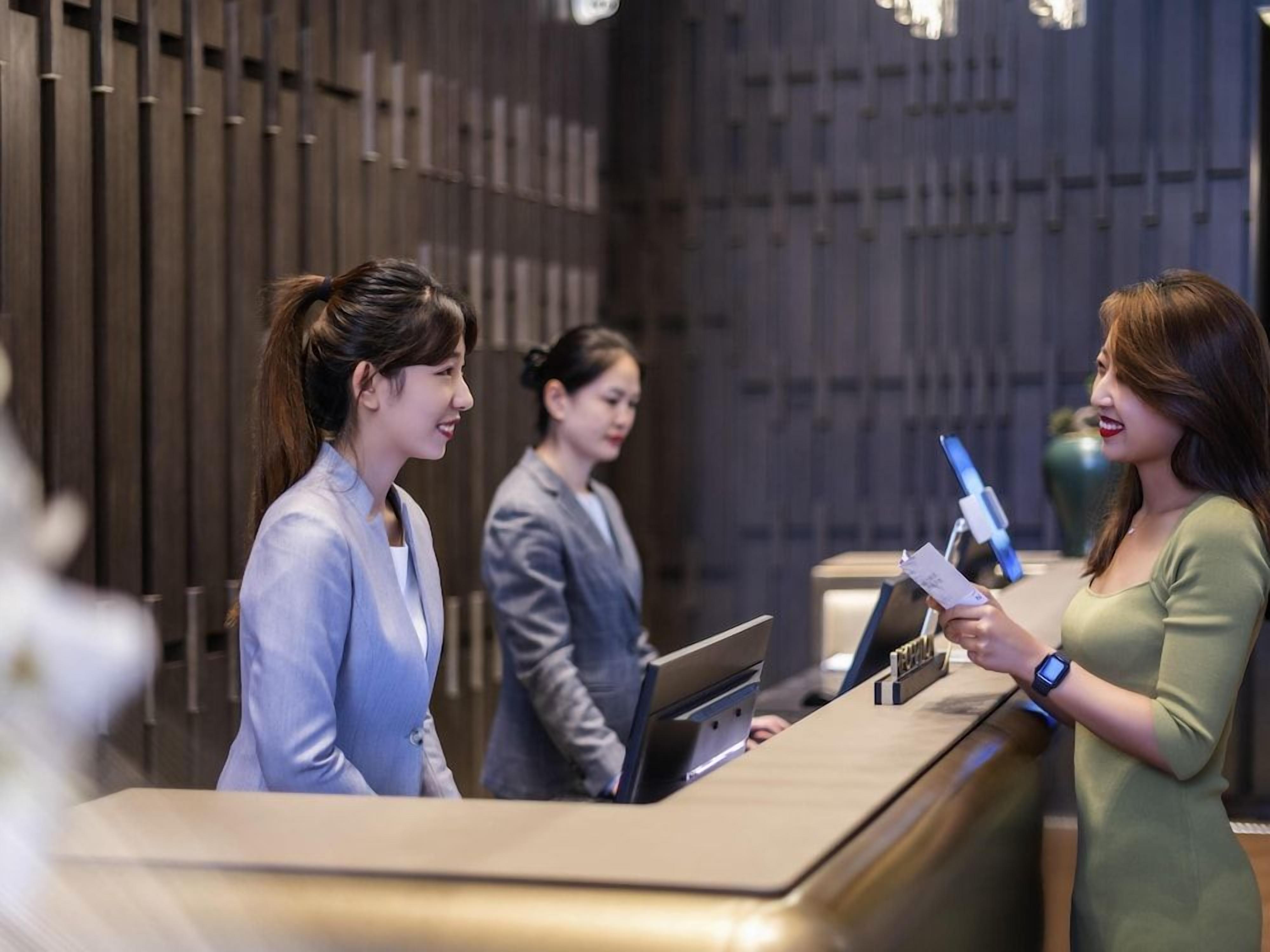 A reception desk with a modern design, equipped with a computer and a digital display.