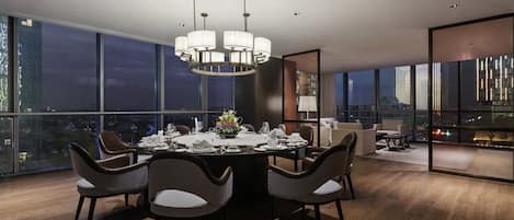 A modern dining area with a round table, chairs, and a chandelier.