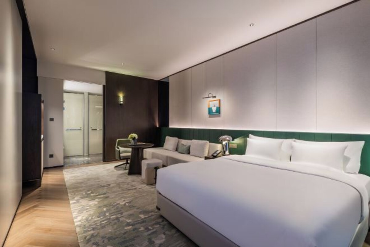 Una habitación de hotel moderna con una cama grande, un rincón de descanso y una mesita.