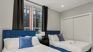 Camera d'albergo con due letti, un'ampia finestra, un armadio e un comodino.