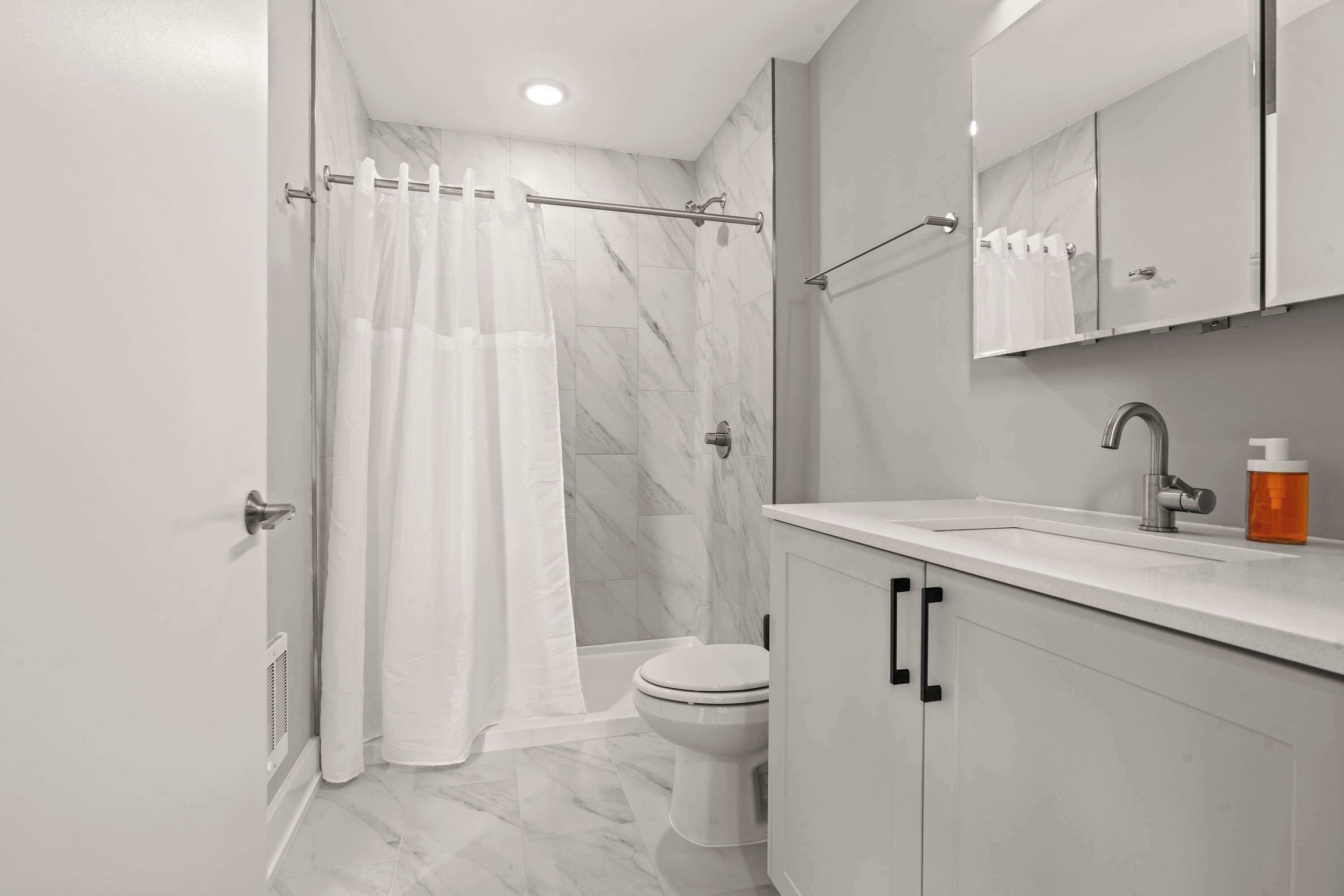 A modern bathroom with a shower, toilet, and vanity.