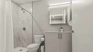 A bathroom with a shower, toilet, and a cabinet with a mirror above it. - Luxury Studio | 1 Bed | Northern Liberties (Philadelphia)