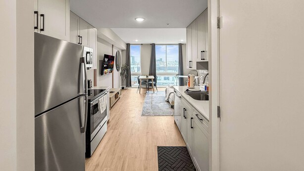 A modern kitchen with stainless steel appliances, a dining area with a view, and a large window. - Luxury Studio | 1 Bed | Northern Liberties (Philadelphia)