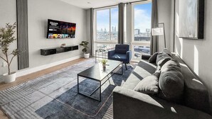 Una sala de estar moderna con un ventanal grande, un sofá, una mesa de centro y un televisor montado en la pared.