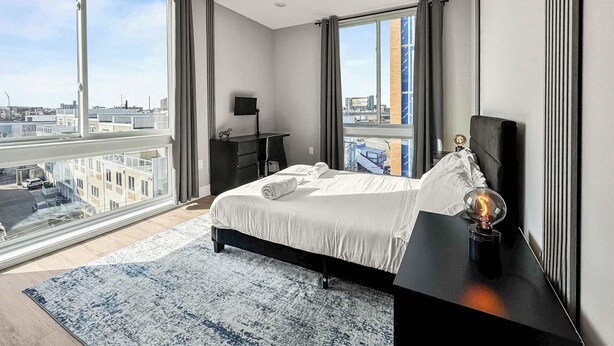 Habitación de hotel moderna con una cama grande, un escritorio y vistas a la ciudad.