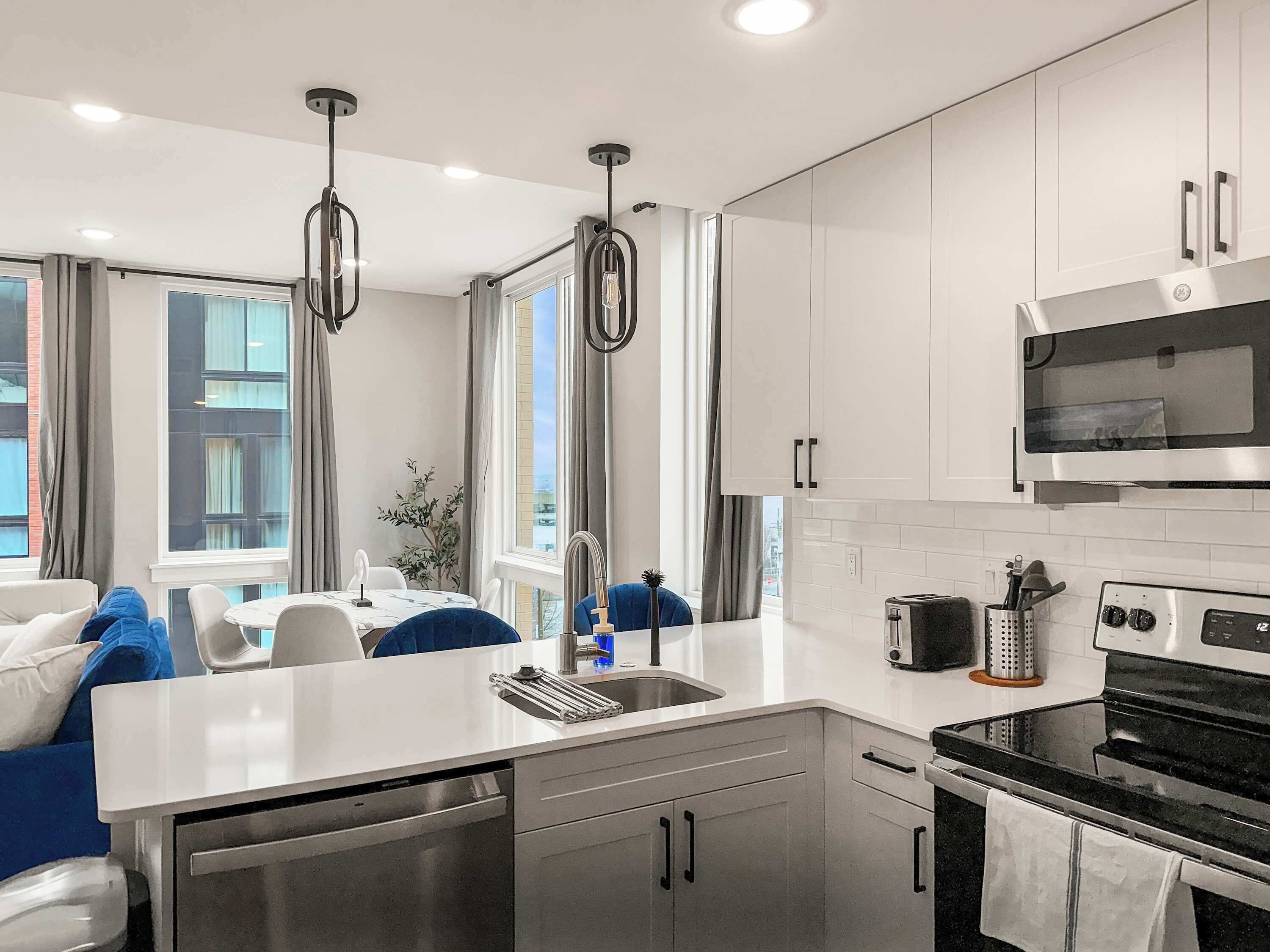 A modern kitchen with white cabinetry, stainless steel appliances, and a central island.