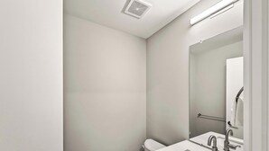 A small, clean bathroom with a toilet, sink, and mirror.