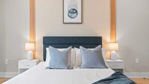 A neatly made bed with a dark headboard, two bedside lamps, and a framed artwork above. - Luxury 1BD | 2 Beds | Northern Liberties (Philadelphia)