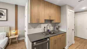 A compact kitchen with wooden cabinets, a stainless steel sink, and a dishwasher.