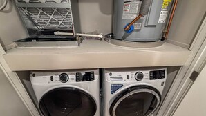 A compact laundry area with two front-loading washing machines and a stacked dryer.