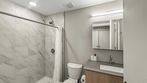 A modern bathroom with a shower, toilet, and sink.