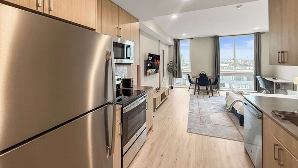 Eine moderne Küche mit Edelstahlgeräten, Holzschränken und einem Essbereich mit Blick auf die Stadt.
