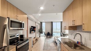 Eine moderne Küche mit Holzschränken, Edelstahlgeräten und einem großen Fenster mit Blick auf die Stadt.
