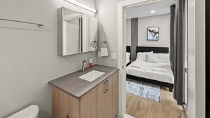A modern hotel room with a bathroom, a bed, and a view of the hallway. - Luxury 2BD | 4 Beds | Northern Liberties (Philadelphia)