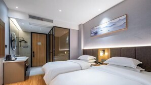 A hotel room with two beds, a bedside table with a lamp, a large window, and a painting on the wall. - Homeinn Ripple Yun Hotel (Guangde Bus Passenger Transport Center) (Guangde)