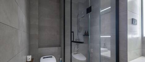 Un baño moderno con ducha de vidrio, inodoro y lavamanos.