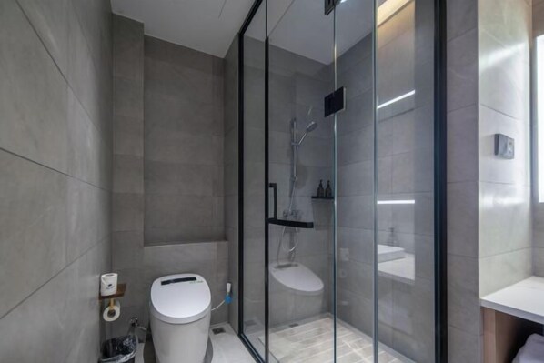Un baño moderno con ducha de vidrio, inodoro y lavamanos.