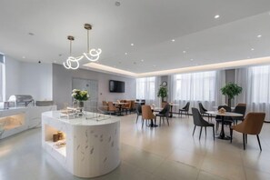 A modern hotel lobby with a central marble reception desk, dining area with round tables and chairs, and a flat-screen TV mounted on the wall. - Homeinn Ripple Yun Hotel (Guangde Bus Passenger Transport Center) (Guangde)