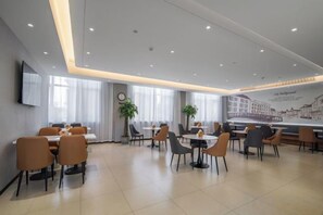 A modern dining area with tables and chairs, a clock, and a wall-mounted television. - Homeinn Ripple Yun Hotel (Guangde Bus Passenger Transport Center) (Guangde)
