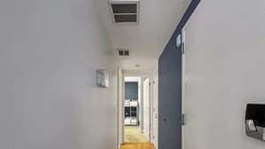 A narrow hallway with wooden flooring leading to a room with a bed. - Luxury 2BD | 5 Beds | Rittenhouse (Philadelphia)