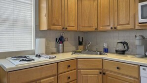 A compact kitchen with wooden cabinets, a built-in microwave, a coffee maker, and a sink. - Luxury 2BD | 5 Beds | Rittenhouse (Philadelphia)