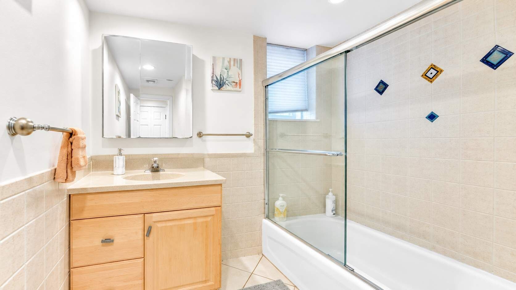 A bathroom with a glass-enclosed shower, a wooden vanity, and a mirror above the sink.