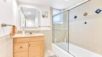A bathroom with a glass-enclosed shower, a wooden vanity, and a mirror above the sink.