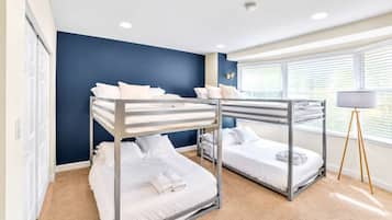 A room with bunk beds, a standing lamp, and a window with blinds.