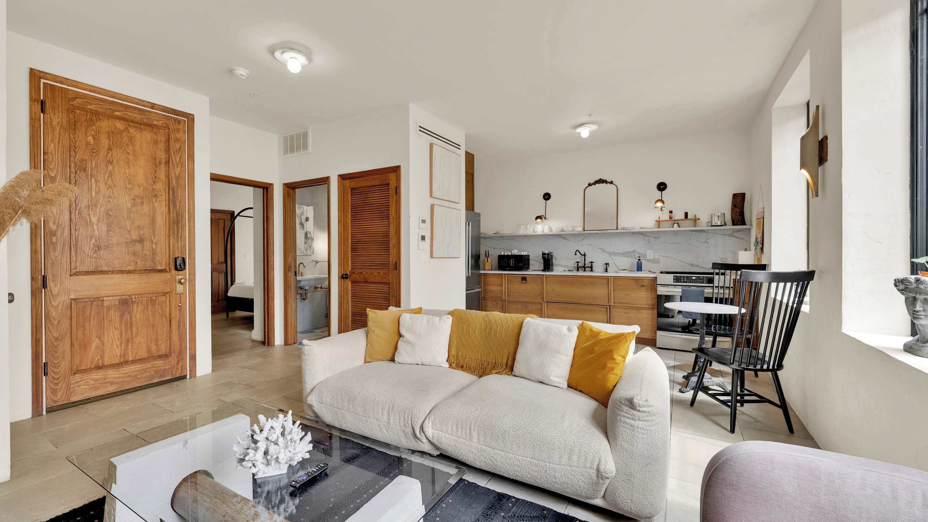 Una sala de estar con sofá, mesa de centro y cocina al fondo.