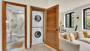 A modern bathroom with a marble shower, a double LG washing machine, and a wooden door. - Luxury 1BD | 1 Bed | South St (Philadelphia)