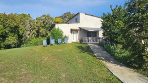 A house with a covered patio, surrounded by a well-maintained lawn and trees. - Villa near Solenzara (Ventiseri)