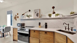Eine moderne Küche mit Einbauofen, Mikrowelle und Spüle, Holzschränken und Dekorationen auf den Regalen.
