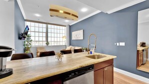 A modern kitchen with a central island, built-in dishwasher, and a window overlooking a cityscape.