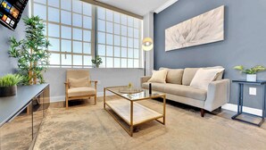A modern living room with a sofa, armchair, coffee table, and large windows.