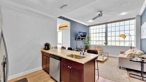 A modern kitchen with a central island, a dining area with a sofa, and a large window with a view.