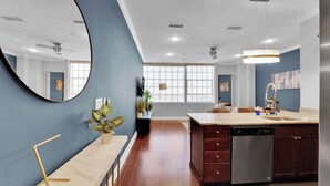 A modern kitchen with a large island, a dishwasher, and a dining area with a table and chairs.