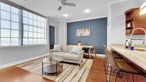 A modern living room with a sofa, a round coffee table, and a dining area with a table and chairs.