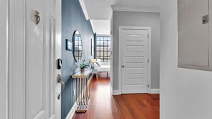 A hallway with a wooden floor, a white door, and a blue wall with a window.