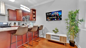 Een moderne keuken met een bar, een flatscreen televisie en een potplant.