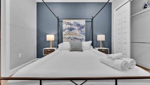Een slaapkamer met een groot bed, twee nachtkastjes met lampen, een schilderij aan de muur en een kledingkast.