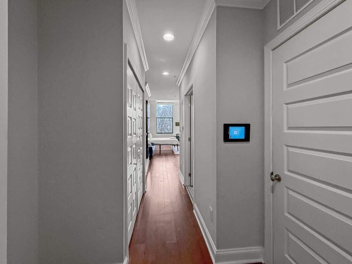 A hallway with a wooden floor, white doors, and a digital lock on the right door.