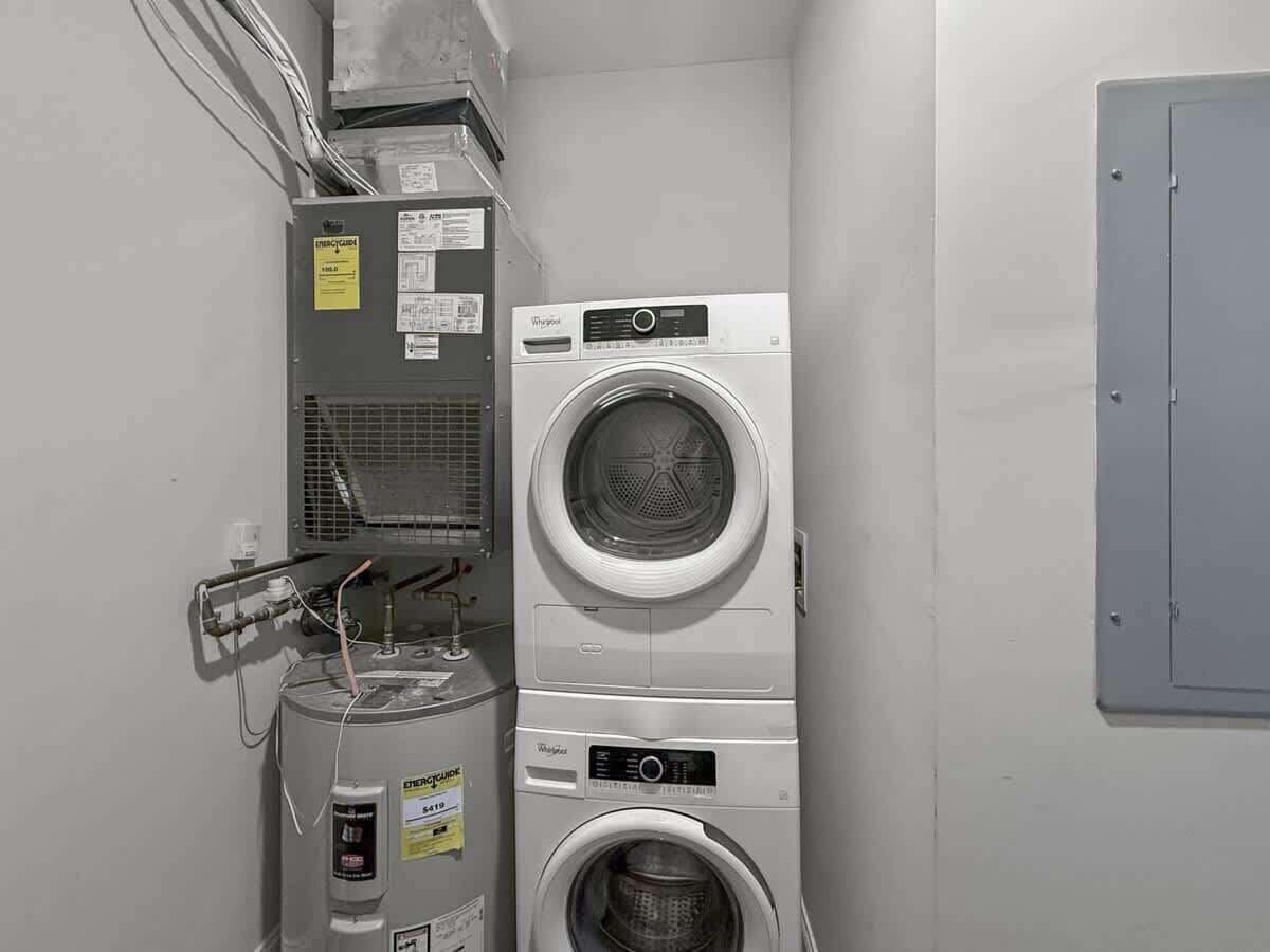 A laundry room with two stacked Whirlpool washers and a water heater.