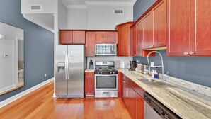 A modern kitchen with stainless steel appliances, wooden cabinets, and a marble countertop.
