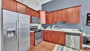A kitchen with stainless steel appliances, wooden cabinets, a built-in microwave, and a water dispenser.